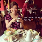 Holding a cup of tea, with sandwiches on the table